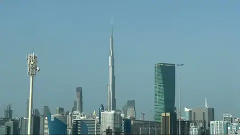 Burj Khalifa rises fully above central Dubai towers in bright daylight.