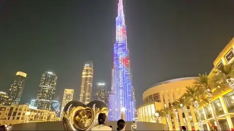Night Burj Khalifa with LED lights, heart sculpture and palm-lined plaza.