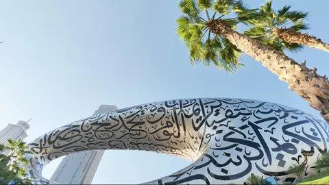 Wide low-angle view of the Museum of the Future with palms and skyline.