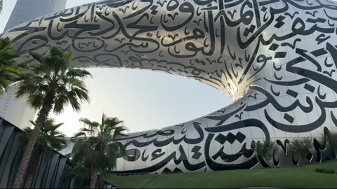 Low-angle view of the Museum of the Future with palms and sun behind.