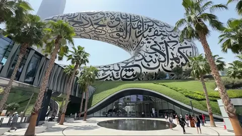 Daytime front view of the Museum of the Future with palms, lawn, and pool.